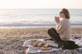 Woman having picnic at beach with tea in thermos.