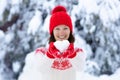 Young woman in knitted sweater holding heart shape snow ball in winter. Girl in family snow fight game. Female in knit handmade