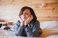 Young woman in a knitted sweater relaxing on a bed in a countryhouse