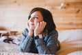 Young woman in a knitted sweater relaxing on a bed in a countryhouse