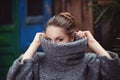Young woman in a knitted turtleneck sweater covering her face. Close up