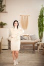 Young woman in a knitted white dress sweater with a knitted retro shawl. Girl in vintage romantic interior is dancing with a hand- Royalty Free Stock Photo