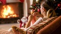 Woman knitting in armchair next to burning fireplac eand glowing Christmas tree Royalty Free Stock Photo