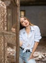 Young woman in knotted shirt posing near steel mesh fencing inside destroyed building