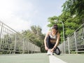 Young woman lace up her shoe ready to workout on exercising in the park with warm light sunshine in morning.