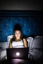 Young woman with laptop in bed at dark night Royalty Free Stock Photo