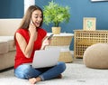 Young woman with laptop and credit card talking on mobile phone at home. Online shopping Royalty Free Stock Photo