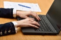 Young woman with laptop - indoor. Women hands working with laptop, document and pen on a background Royalty Free Stock Photo