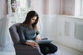 Young woman with laptop sitting on armchair at home Royalty Free Stock Photo