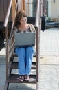Young woman with laptop on the steps of old train