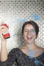 Young woman laughing and spraying party string over herself