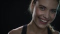 Young woman laughnig in black studio. Close up of fit girl with piercing in nose