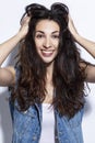 Young woman laughs. Beautiful brunette in jeans with long hair. Positiveness and happiness. White background. Close-up