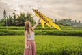 Young woman launches a kite in a rice field in Ubud, Bali Island, Indonesia