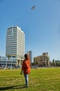 A young woman launches a kite in the sky over Tel Aviv on a bright sunny day