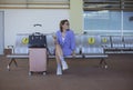 A young woman in a lavender blazer anxiously waits for her ride to pick her up while outside the arrival area of an airport Royalty Free Stock Photo