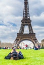 Young woman laying on the gras in front of Eiffel tower and using a smart phone