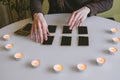 Woman lays out black cards on the table with candle lights
