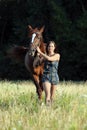 Young woman leading horse on a meadow