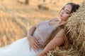 Young woman lean on haystack walking in summer evening, beautiful romantic girl outdoors in field at sunset Royalty Free Stock Photo