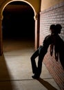 Young Woman Leaning Against Brick Wall at Night Royalty Free Stock Photo