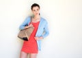 Young woman leaning against white wall with purse Royalty Free Stock Photo