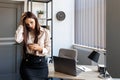 Young woman leaning on a desk holding a mobile phone and with a sad look on her face, looking at the screen, reading and writing a Royalty Free Stock Photo