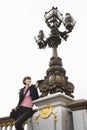 Young Woman Leaning On Ornate Streetlight