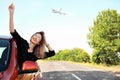 Young woman leaning out of car window and airplane in sky. Summer vacation Royalty Free Stock Photo