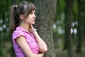 Young woman leaning to tree trunk in summer forest Royalty Free Stock Photo