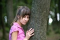 Young woman leaning to tree trunk in summer forest Royalty Free Stock Photo