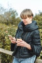 young woman leaning on wooden fence and using her smartphone Royalty Free Stock Photo