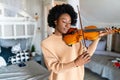 Young woman learning to play violin at home. Romantic african american girl playing violin Royalty Free Stock Photo