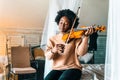 Young woman learning to play violin at home. Romantic african american girl playing violin Royalty Free Stock Photo