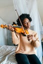 Young woman learning to play violin at home. Romantic african american girl playing violin Royalty Free Stock Photo