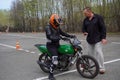 A young woman is learning to ride a motorbike in a motorcycle school. She is taught by a teacher