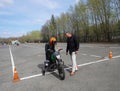 A young woman is learning to ride a motorbike in a motorcycle school. She is taught by a teacher