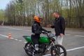 A young woman is learning to ride a motorbike in a motorcycle school. She is taught by a teacher