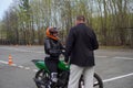 A young woman is learning to ride a motorbike in a motorcycle school. She is taught by a teacher