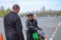 A young woman is learning to ride a motorbike in a motorcycle school. She is taught by a teacher