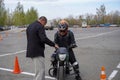 A young woman is learning to ride a motorbike in a motorcycle school. She is taught by a teacher