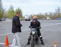 A young woman is learning to ride a motorbike in a motorcycle school. She is taught by a teacher