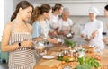 Young woman learns to cook at master class