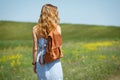 Young woman with a leather backpack in a summer field Royalty Free Stock Photo