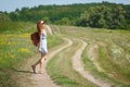 Young woman with a leather backpack on a summer rural road Royalty Free Stock Photo