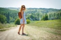 Young woman with a leather backpack on a summer rural road Royalty Free Stock Photo