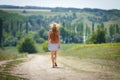 Young woman with a leather backpack on a summer rural road Royalty Free Stock Photo