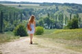 Young woman with a leather backpack on a summer rural road Royalty Free Stock Photo