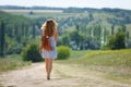Young woman with a leather backpack on a summer rural road Royalty Free Stock Photo