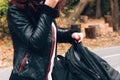 Young woman in leather jacket puts things in backpack on the background of a bike path in the autumn forest Royalty Free Stock Photo